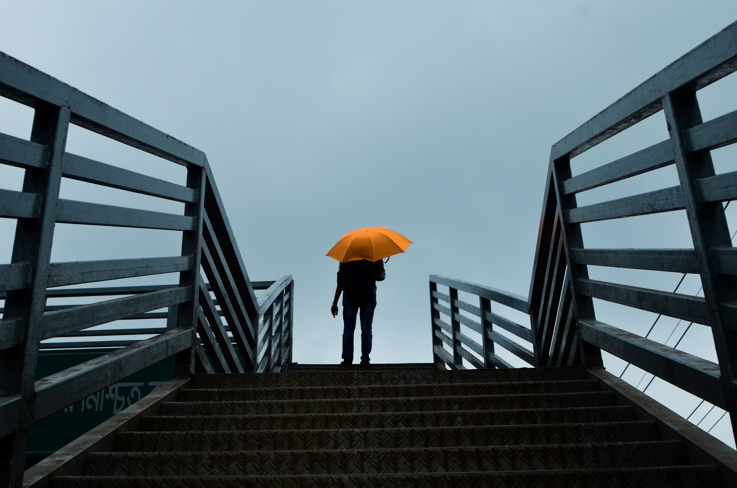 person-holding-umbrella-standing-above-stairs-1695056